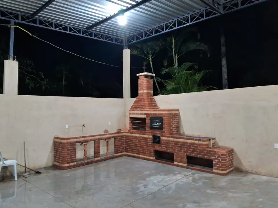 Espaço gourmet em L com churrasqueira, forno e pia em tijolo vermelho